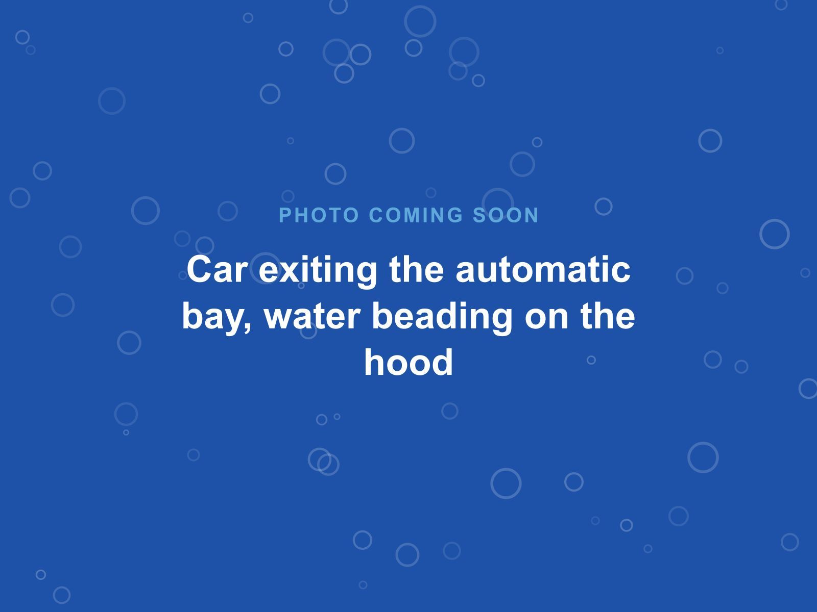 A car leaving the automatic bay with water beading on the hood
